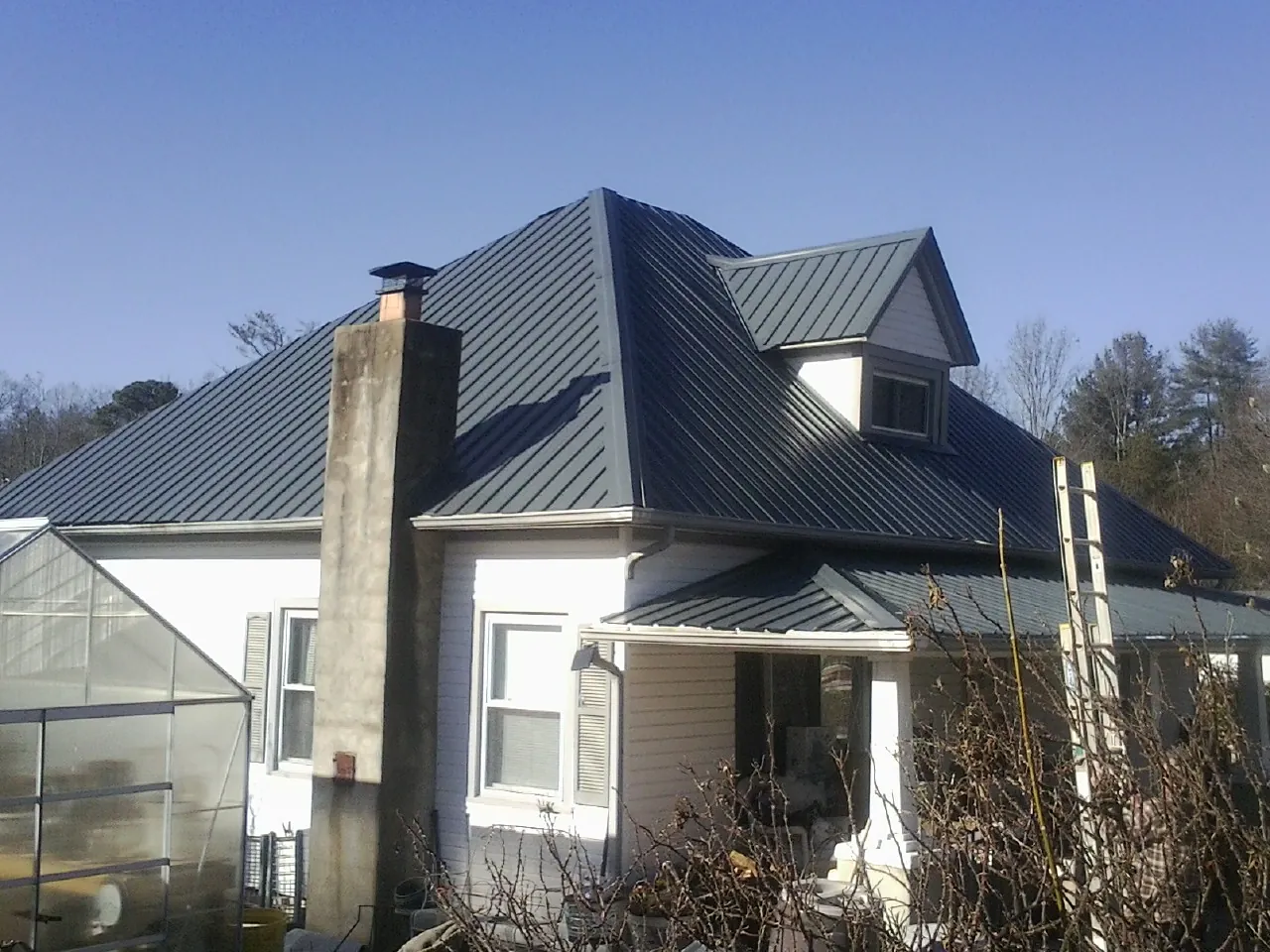 Dark blue standing seam metal roof on a white farmhouse with dormer — Slate & Tile Roof Repair by Roofing Brothers in West Covina