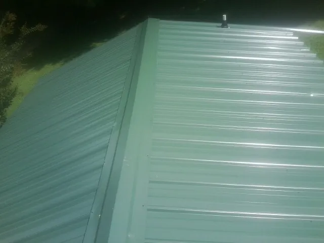 New green metal panels meeting at the ridge of a roof — Flat Roof Repair work by our crew in West Covina