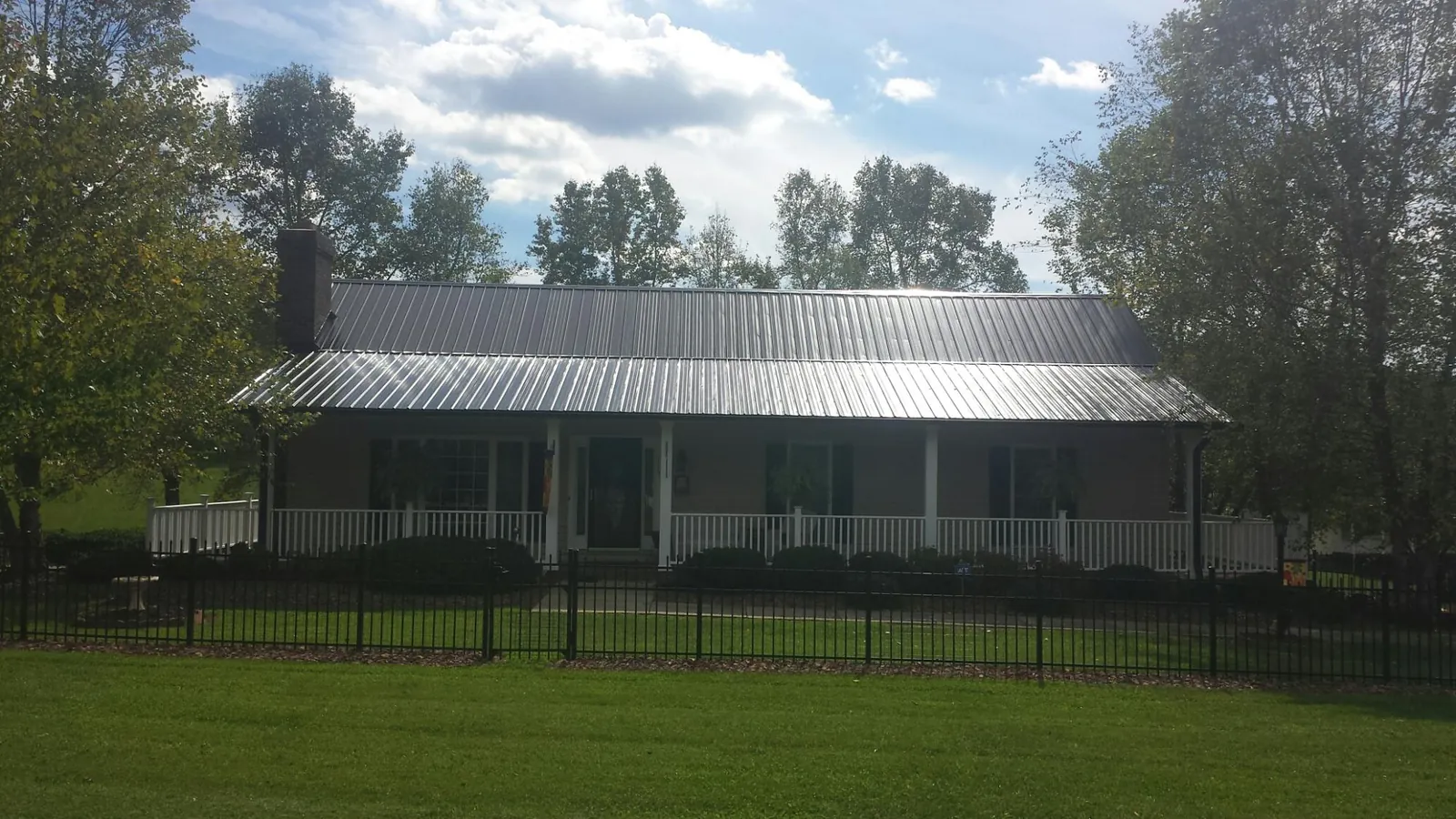 Gray metal roof on a brick ranch with a full width front porch — Gutter Guard Installation work by our crew in West Covina
