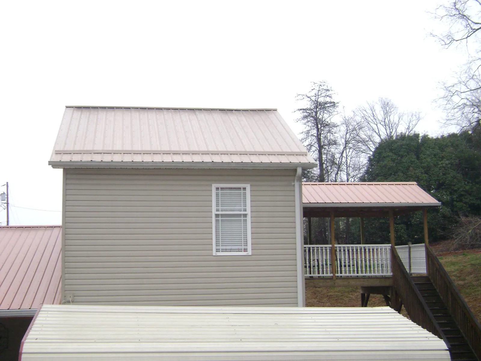 Tan metal roofs on a two story addition and attached porch, from a Roof Replacement job in West Covina