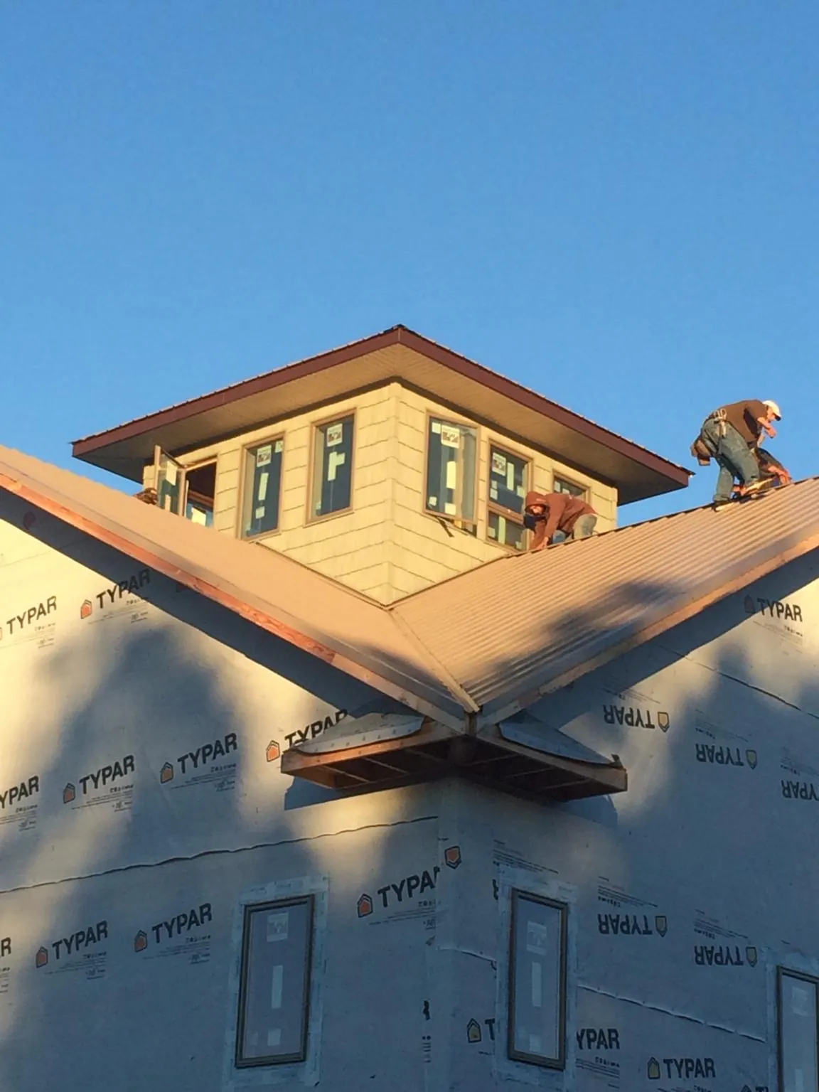 Roofers working around a rooftop cupola on a new metal roof at sunset — Roof Waterproofing in West Covina by Roofing Brothers
